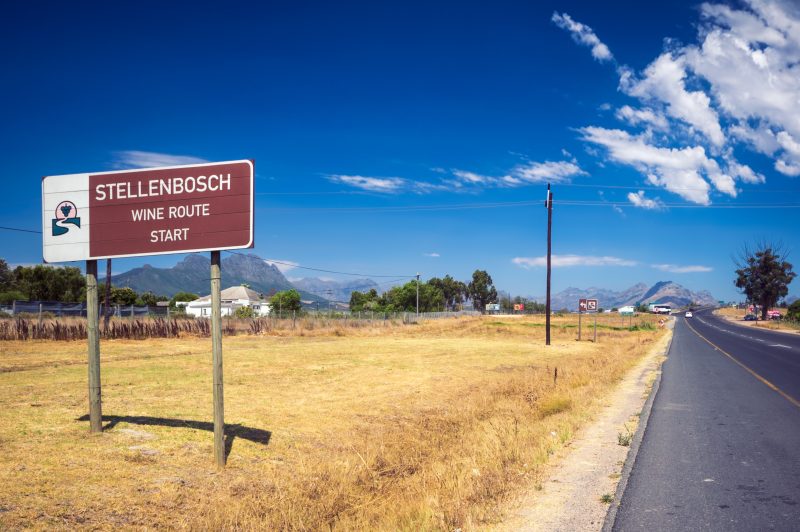 Braunes Straßenschild mit der Aufschrift Stellenbosch Wine Route Start